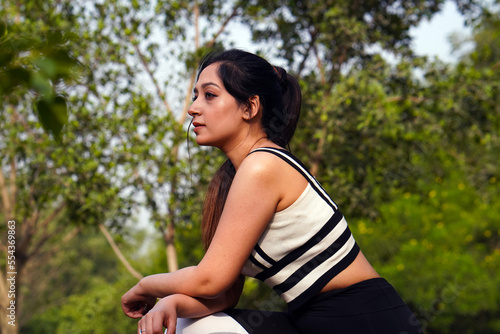 Young sporty Indian woman resting in the park after training
