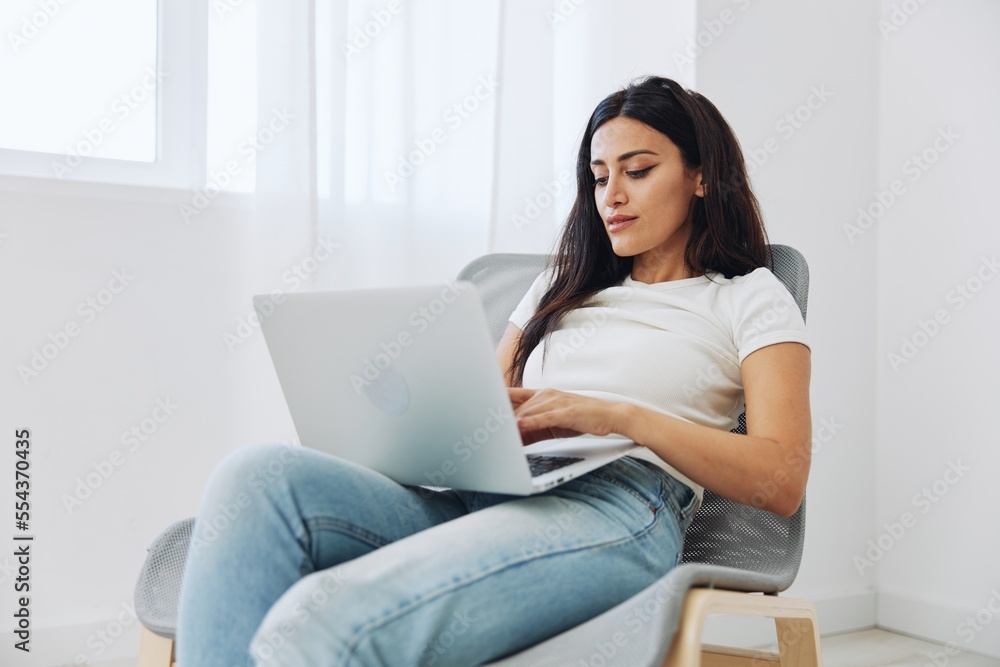 Woman ordering things online via website at online store via laptop at home sitting in chair, technology in business, shopping online Woman ordering things online via website at online store via laptop at home sitting in chair, technology in business, shopping online