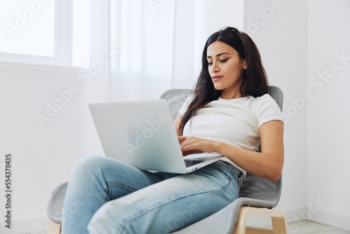 Woman ordering things online via website at online store via laptop at home sitting in chair, technology in business, shopping online