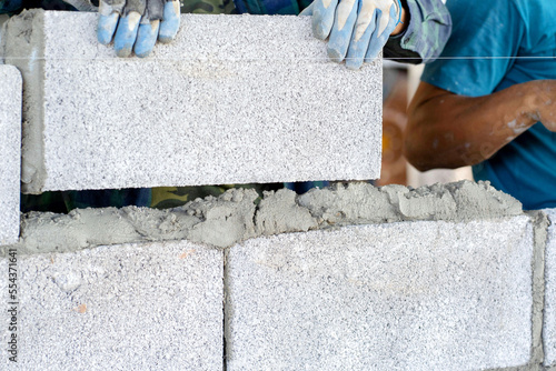 masonry worker make concrete wall by cement block and plaster at construction site