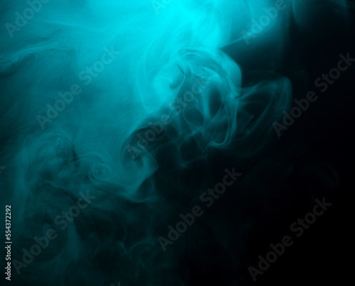 Abstract background of chaotically mixing clouds of turquoise smoke on a background of darkness