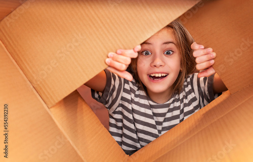 girl in a striped T-shirt opens a cardboard box