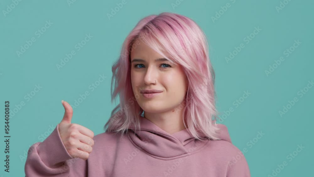 Positive feedback, body language sign concept. Cheerful Charming beautiful positive young woman with pink hair showing thumbs up, looking happy at camera and enjoying posing on green screen background Positive feedback, body language sign concept. Cheerful Charming beautiful positive young woman with pink hair showing thumbs up, looking happy at camera and enjoying posing on green screen background