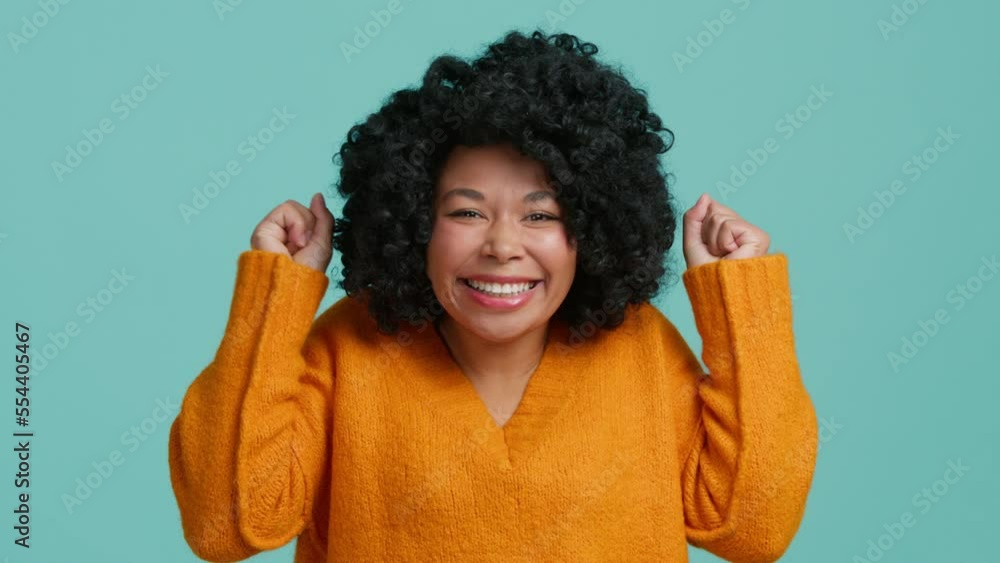 Surprised woman can not believe her win. Excited woman with afro hairstyle raising hands, looking at camera with big eyes and smile shocked by sudden news. Oh my god wow. Studio isolated background Surprised woman can not believe her win. Excited woman with afro hairstyle raising hands, looking at camera with big eyes and smile shocked by sudden news. Oh my god wow. Studio isolated background