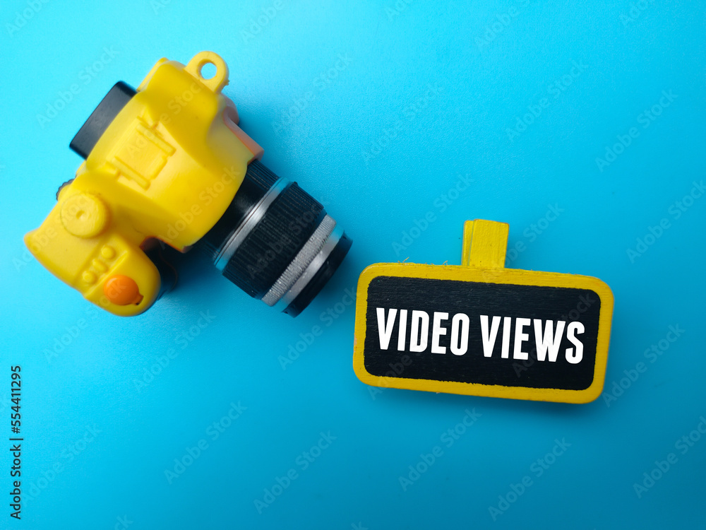 Yellow camera and wooden board with the word VIDEO VIEWS on blue background. Yellow camera and wooden board with the word VIDEO VIEWS on blue background.