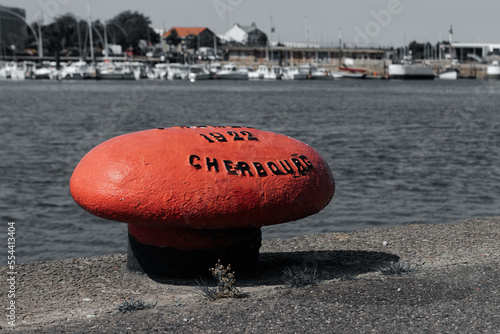 A closeup shot of a red shipping bollard with the port in the background in Cherbourg