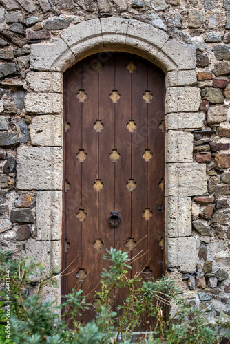 A vertical shot of an old wooden arched door of the medieval building