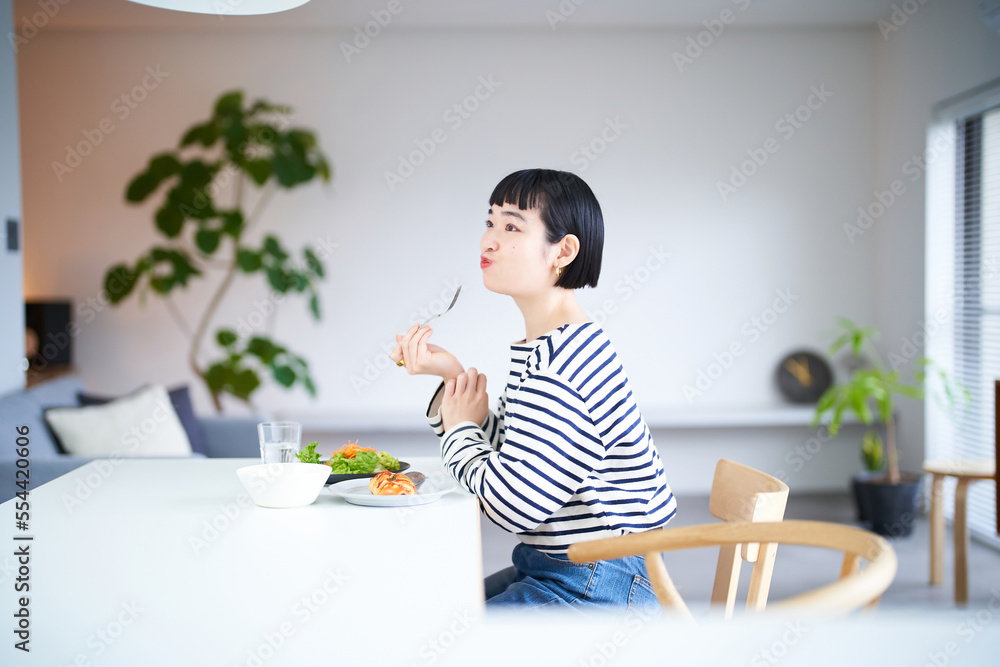 家のダイニングで食事をする女性 
