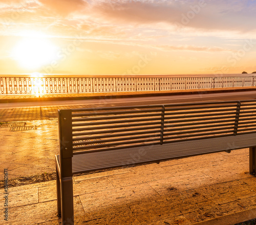 modern metallic bench on sea embarkment with asphalt road and beautiful seashore landscape with amazing cloudy sky