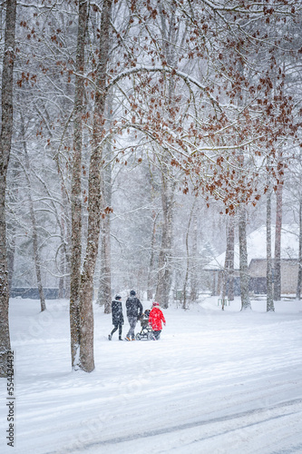 Family walking with small children in the park in winter. Snow cityscape of a street in Baldone. Winter snowstorm.