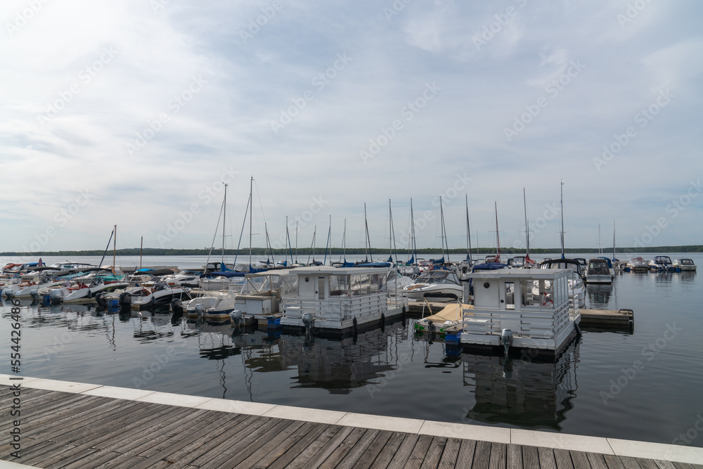 Big Lake Sentenberg. City harbour. Blue sky. Calm water. Lots of boats and yachts at the pier. A beautiful place to relax in nature near the water. Germany. .  Without people