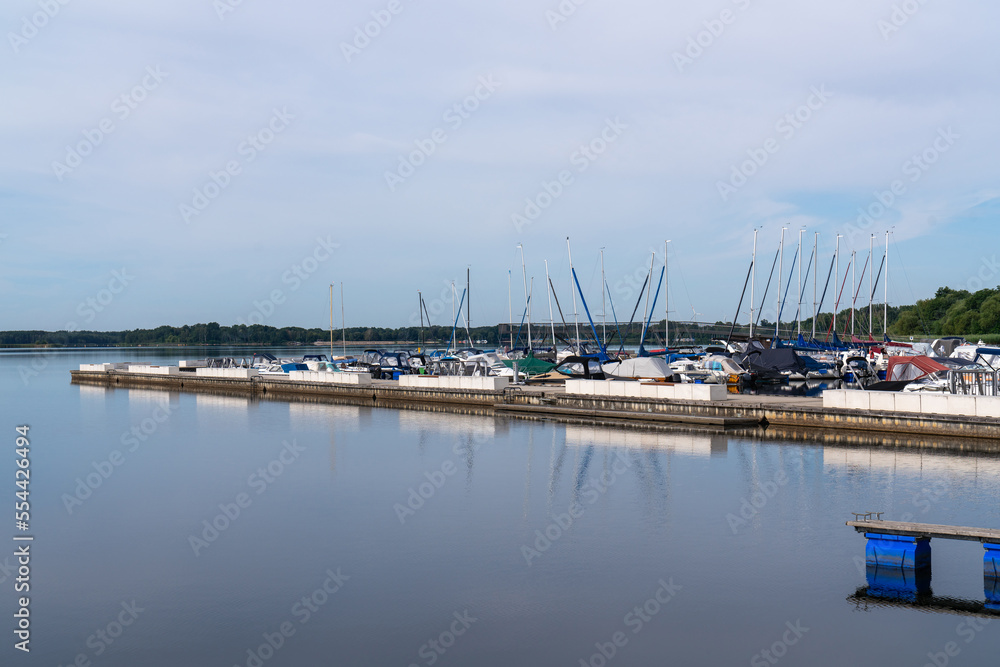 Big Lake Sentenberg. City harbour. Blue sky. Calm water. Lots of boats and yachts at the pier. A beautiful place to relax in nature near the water. Germany. .  Without people