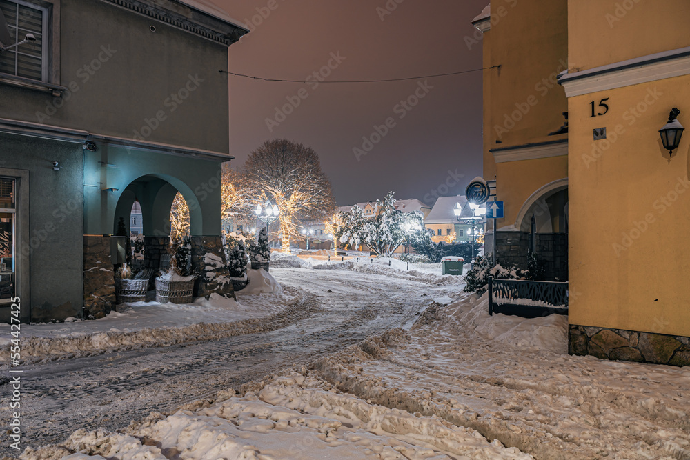 Rynek starego miasta zimą w nocy, Wodzisław Śląski w Polsce zasypany śniegiem z choinkami i światełkami świątecznymi