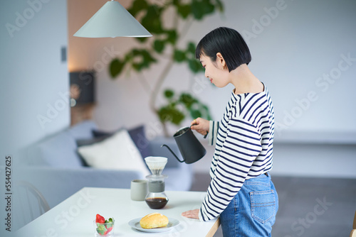 部屋でコーヒーを淹れる若い女性 photo