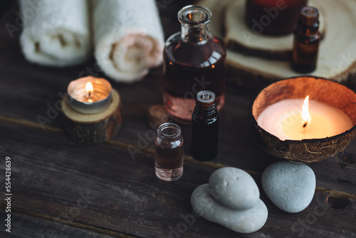 Concept of natural essential organic oils, Bali spa, beauty treatment, relax time. Atmosphere of relaxation, pleasure. Candles, towels, dark wooden background. Alternative oriental medicine