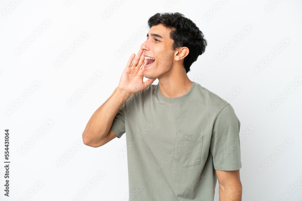 Young Argentinian man isolated on white background shouting with mouth wide open to the side Young Argentinian man isolated on white background shouting with mouth wide open to the side