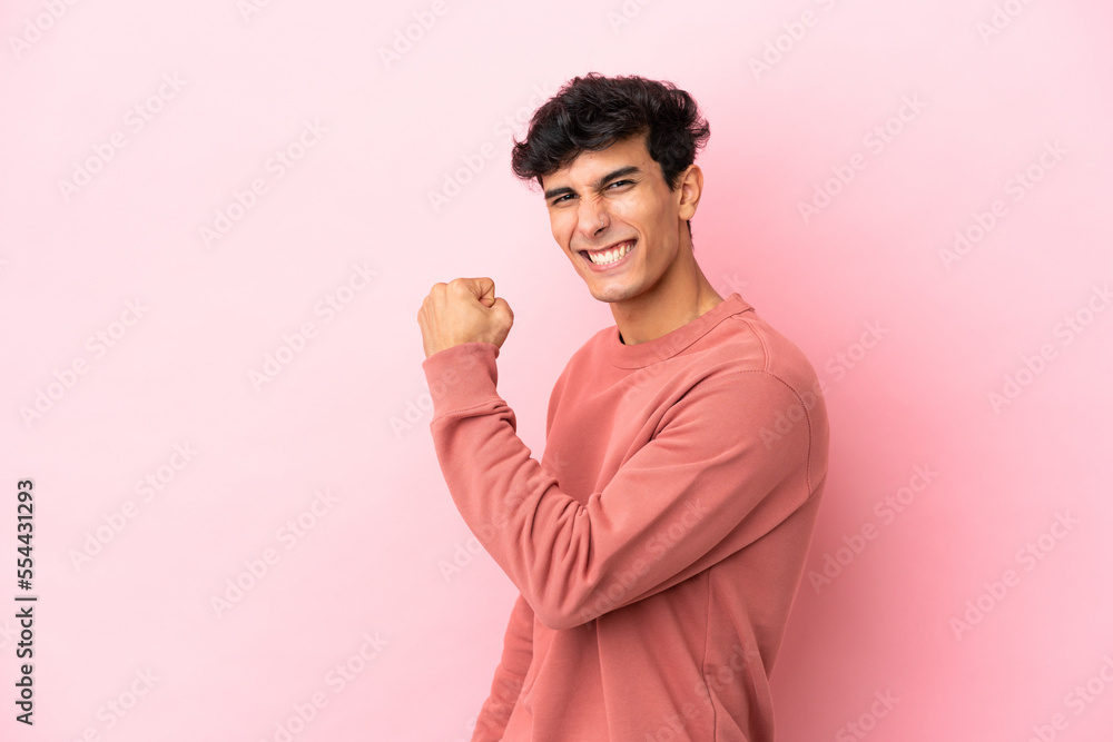 Young Argentinian man isolated on pink background celebrating a victory Young Argentinian man isolated on pink background celebrating a victory