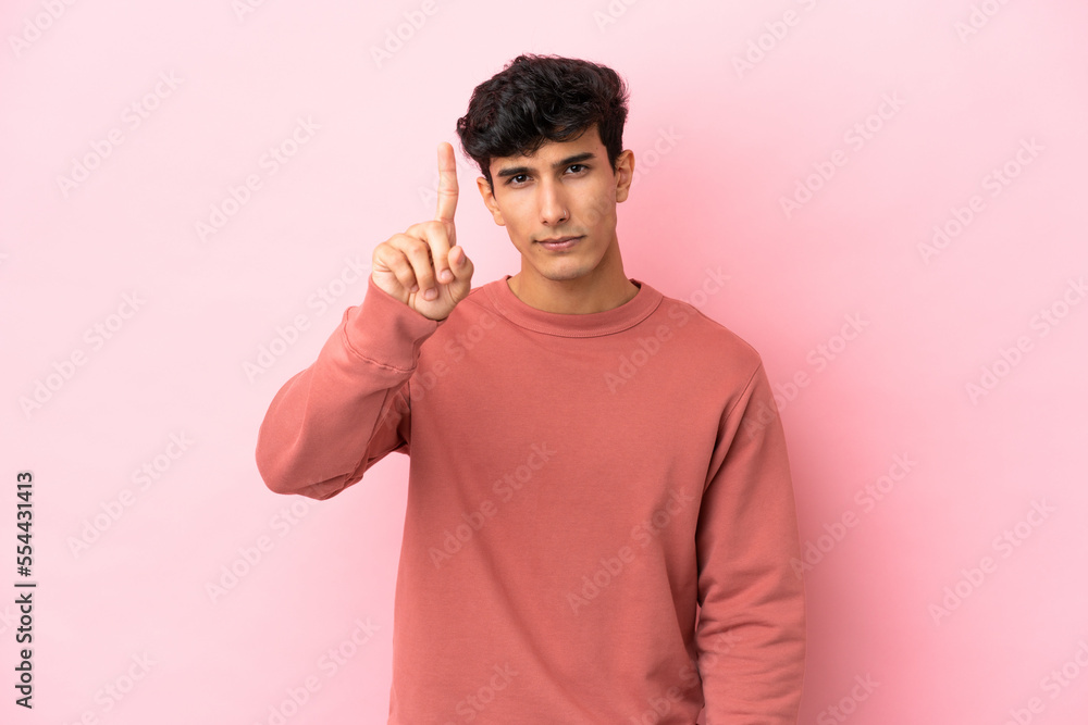Young Argentinian man isolated on pink background counting one with serious expression Young Argentinian man isolated on pink background counting one with serious expression