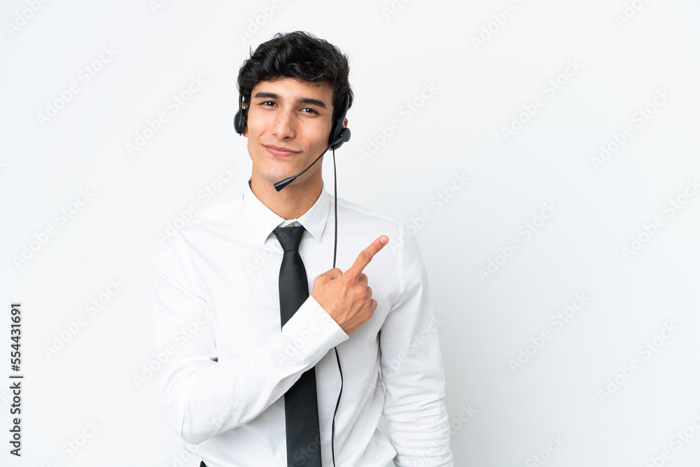Telemarketer man working with a headset isolated on white background pointing to the side to present a product Telemarketer man working with a headset isolated on white background pointing to the side to present a product