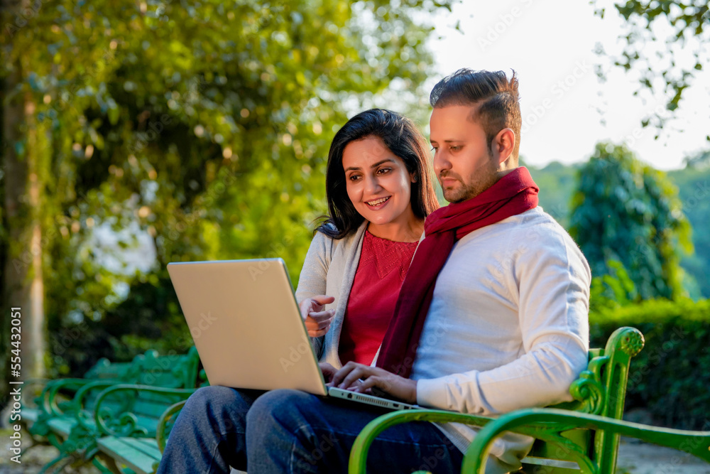 Young indian couple using laptop at park. Young indian couple using laptop at park.
