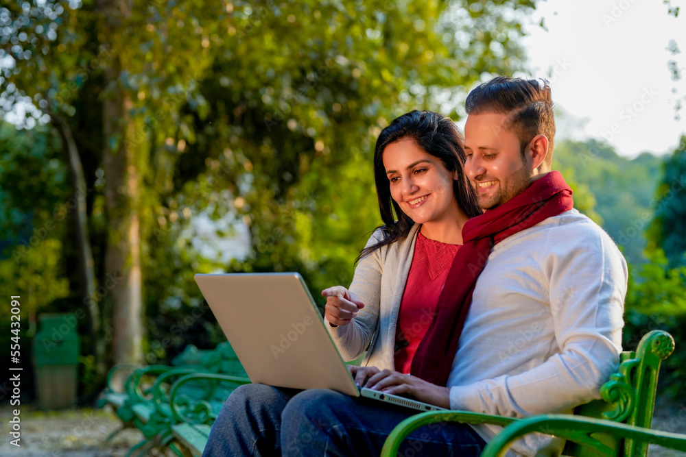 Young indian couple using laptop at park. Young indian couple using laptop at park.