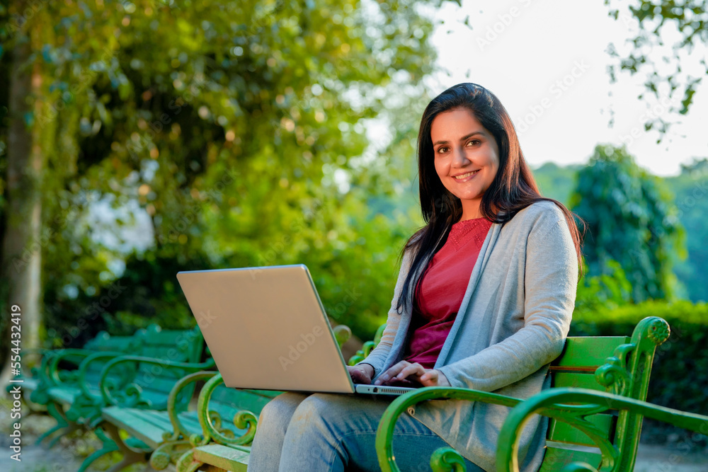 Young Indian woman using laptop at park Young Indian woman using laptop at park