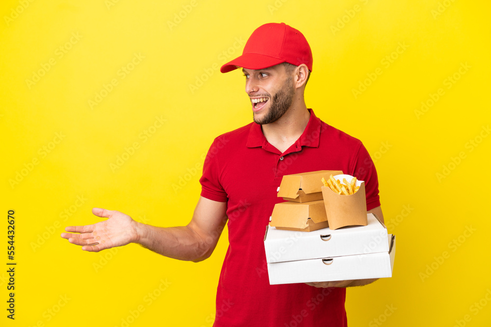 pizza delivery man picking up pizza boxes and burgers over isolated background with surprise expression while looking side pizza delivery man picking up pizza boxes and burgers over isolated background with surprise expression while looking side