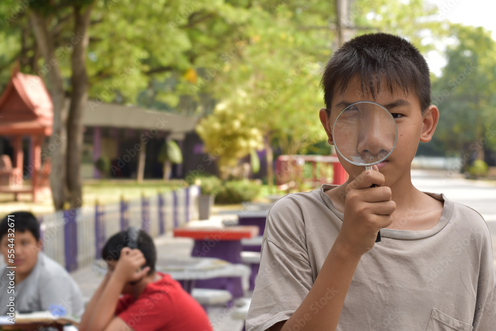 Portrait young asian boy holds magnifying glass in front of his nose and mouth to show his tooth, soft and selective focus. Portrait young asian boy holds magnifying glass in front of his nose and mouth to show his tooth, soft and selective focus.