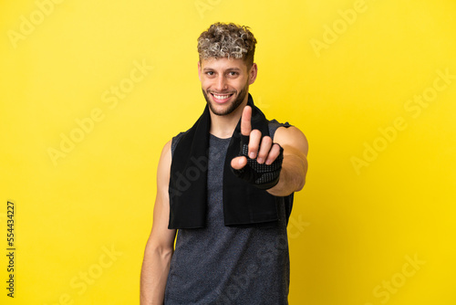 Sport caucasian man isolated on yellow background showing and lifting a finger