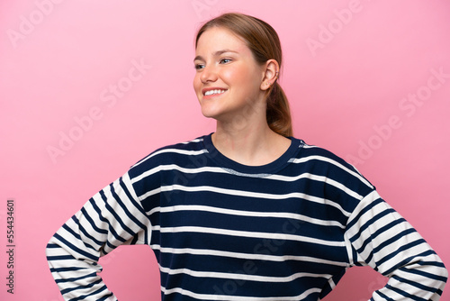 Young caucasian woman isolated on pink background posing with arms at hip and smiling