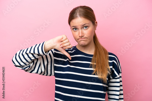 Young caucasian woman isolated on pink background showing thumb down with negative expression