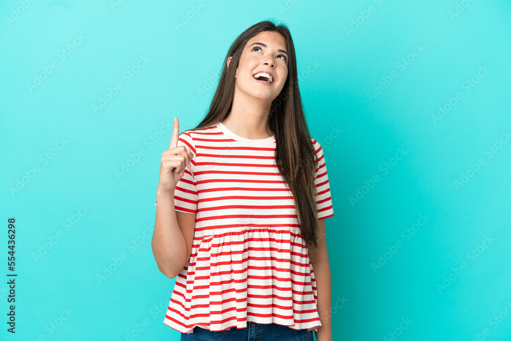 Young Brazilian woman isolated on blue background pointing up and surprised Young Brazilian woman isolated on blue background pointing up and surprised