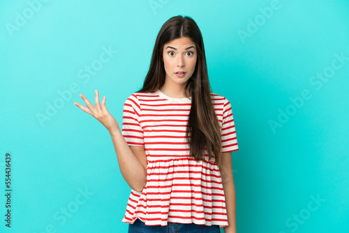 Young Brazilian woman isolated on blue background making doubts gesture
