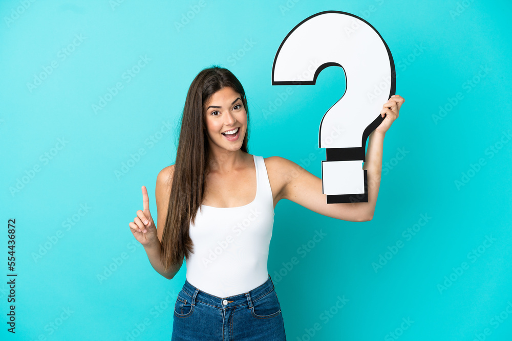 Young Brazilian woman isolated on blue background holding a question mark icon Young Brazilian woman isolated on blue background holding a question mark icon