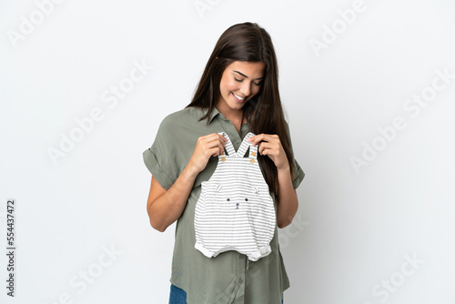 Young Brazilian woman isolated on white background pregnant and holding baby clothes