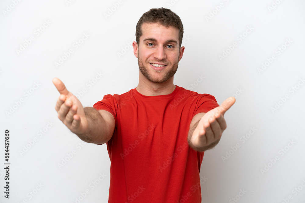 Fototapeta premium Young caucasian man isolated on white background presenting and inviting to come with hand