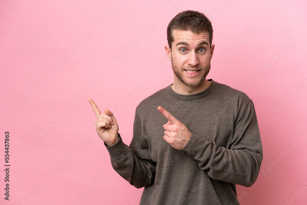 Young caucasian man isolated on pink background frightened and pointing to the side Young caucasian man isolated on pink background frightened and pointing to the side