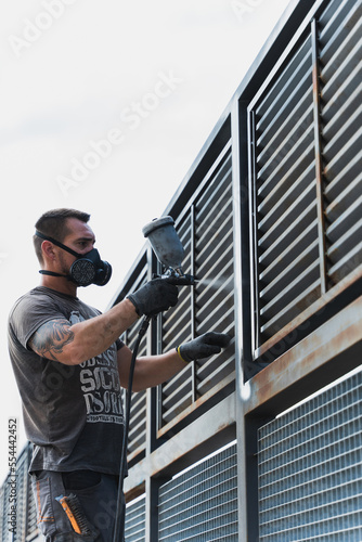 Painter with a spray gun painting bars