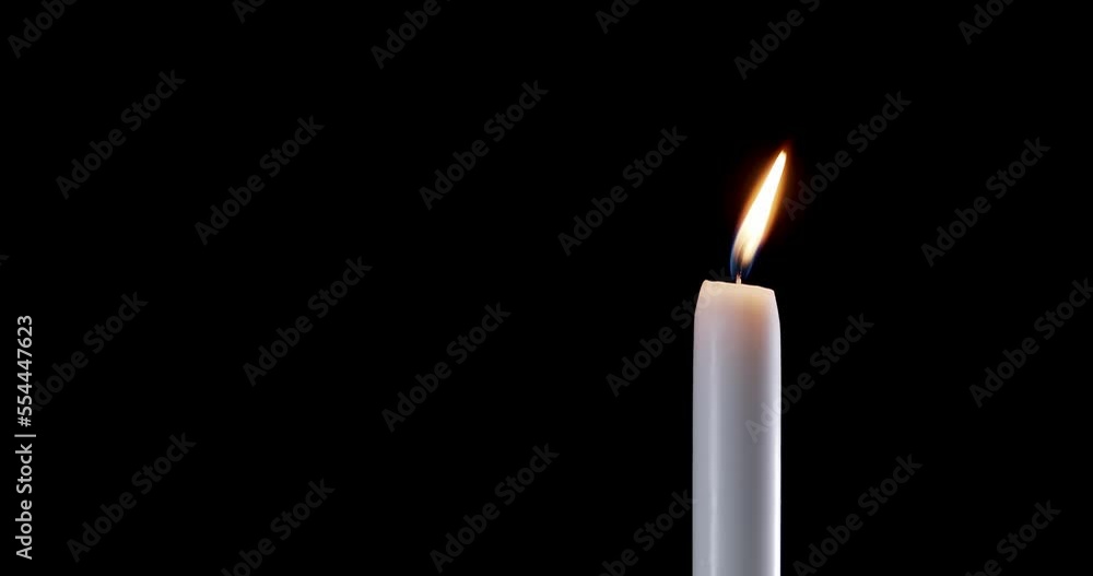 A single white candle burning. Isolated candle slow motion burning with dark background. White paraffin candle with yellow shades burns on a black background. Slow motion. A single white candle burning. Isolated candle slow motion burning with dark background. White paraffin candle with yellow shades burns on a black background. Slow motion.