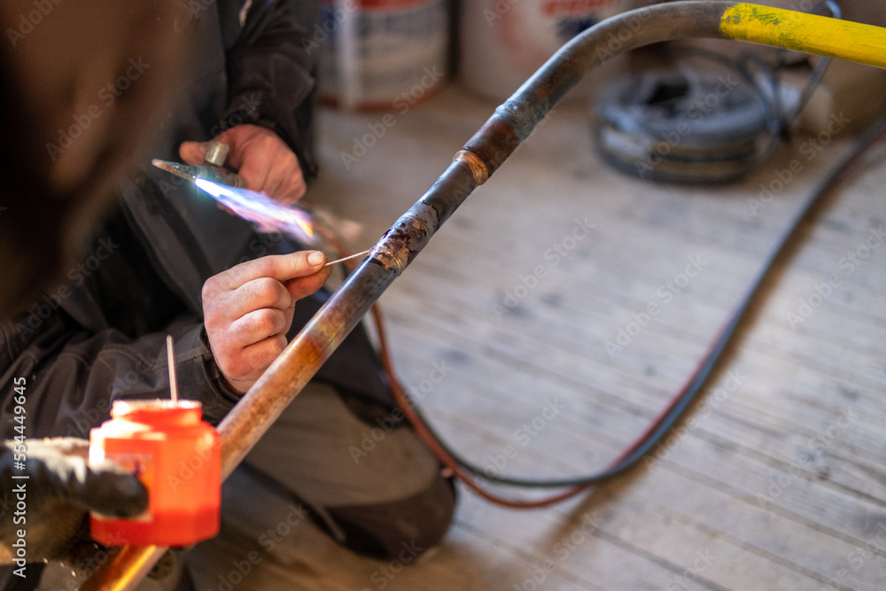 Man welding a gas pipe with flames 