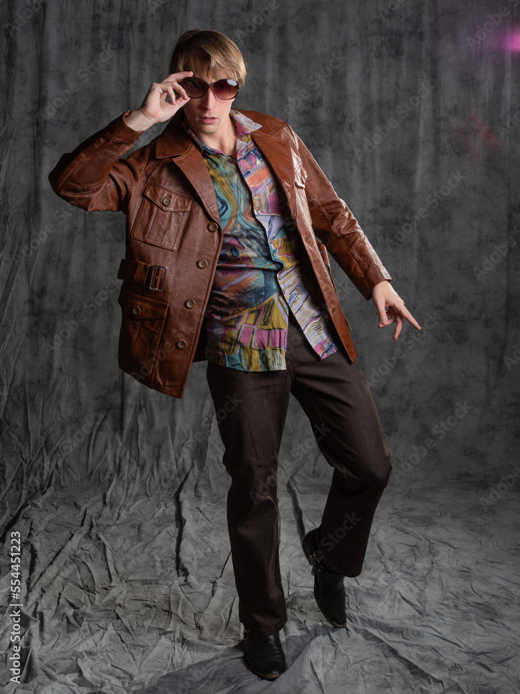 confident dude in a colorful shirt and brown leather jacket, a portrait in sunglasses in the studio on a gray background confident dude in a colorful shirt and brown leather jacket, a portrait in sunglasses in the studio on a gray background