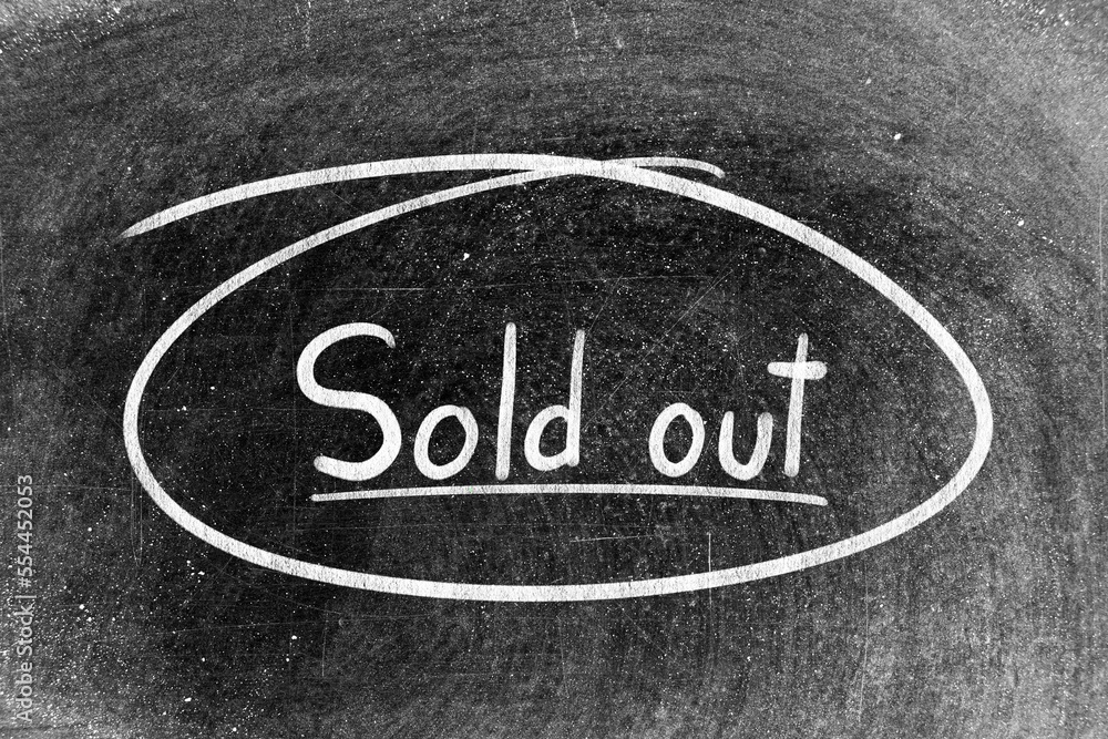 White chalk hand writing in word sold out and circle shape on blackboard background