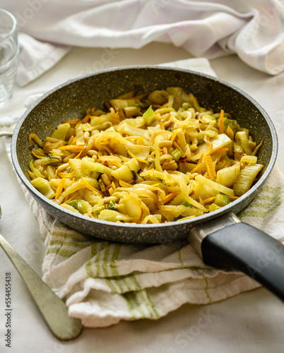 Skillet with sautéed fennel with orange. Traditional French dish. Fennel, pine nuts and orange
