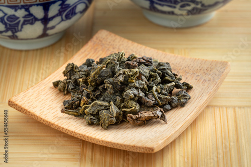 Bamboo plate with Chinese  Ti Kuan Yin organic oolong tea dried tea leaves close up   photo