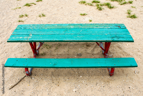 An old, bright green picnic bench on sand on an overcast day. Image has copy space. photo