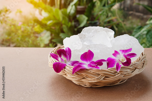 Basket of Crystal clear alum stones or Potassium alum placed outdoor, decorated with flowers. Useful for beauty and spa treatment. Use to treat body odor under the armpits as deodorant and make water photo