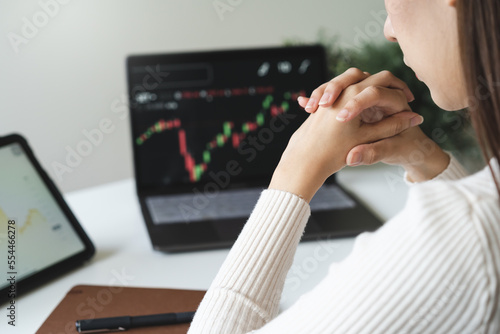 Fotografie Financial investment in exchange stock concept, Young woman investor looking at laptop monitor to research the stock market on the digital marketplace platform at home