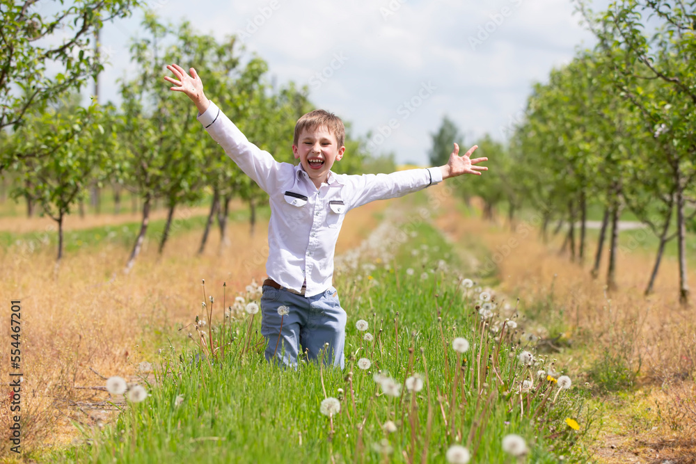 Happy boy rejoices in the spring garden. School summer holidays have begun.