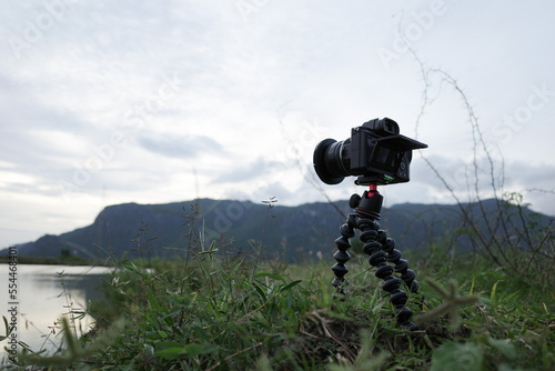 Camera on small tripod with nature mountain landscape, photo trip, lifestyle support for travel photographer and video