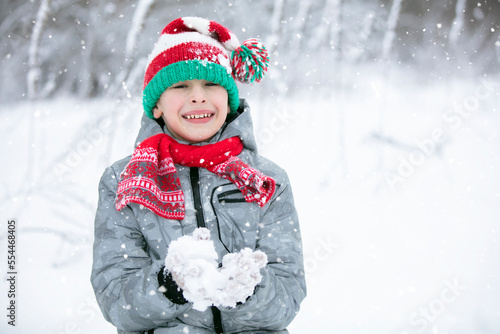 Portrait of a boy in a winter hat. Winter, outside, snow. A child plays with snow. Happy child in winter.